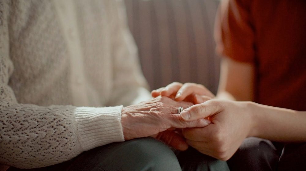 A caregiver holding a patient's hands at The Sanctuary